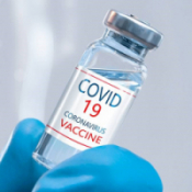 Blue glove holding a vial of COVID-19 vaccine