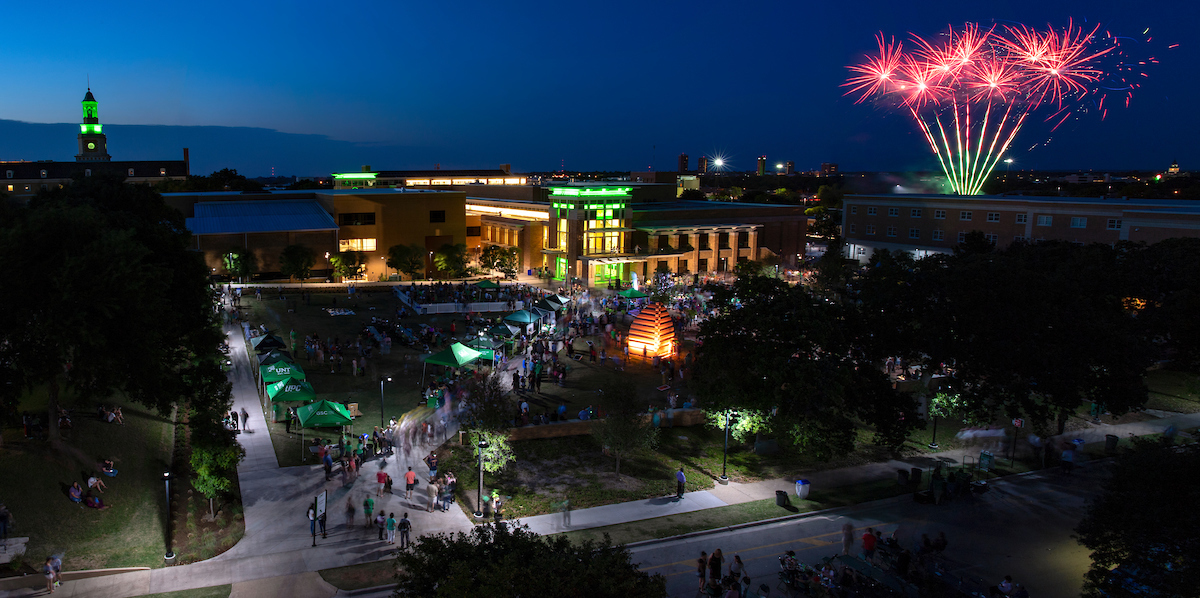 Picture of UNT campus with red fireworks in background