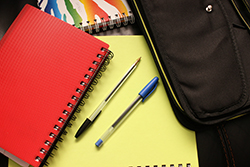 black and blue pens beside red colored notebook