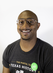 Picture of Staff Senator Joshua Sylve'. Joshua has a bald head, black glasses and a black t-shirt that reads, "The Portal to Texas History." Joshua is smiling against a white background
