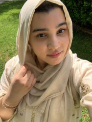 Staff Success Stories Winner Nausheen Qureshi. Qureshi is weird a beige hijab. Qureshi is taking a selfie and standing outside in grass