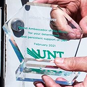 Hands holding clear glass hexagon award with green Brand Ambassador engraving